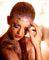 Creative makeup by Saskatoon Makeup Artist Jennilee Cardinal-Schultz using Biodegradable Glitter. Woman with glittery makeup and body art against a bright background