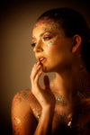Creative makeup by Saskatoon Makeup Artist Jennilee Cardinal-Schultz using Biodegradable Glitter. Woman with artistic makeup and body art against a neutral background