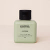 A 75 ml bottle of 'routine. crème' by lucy in the sky, featuring a pale sage green body and a black flip-top cap, set against a solid cream background.