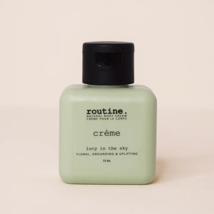 A 75 ml bottle of 'routine. crème' by lucy in the sky, featuring a pale sage green body and a black flip-top cap, set against a solid cream background.