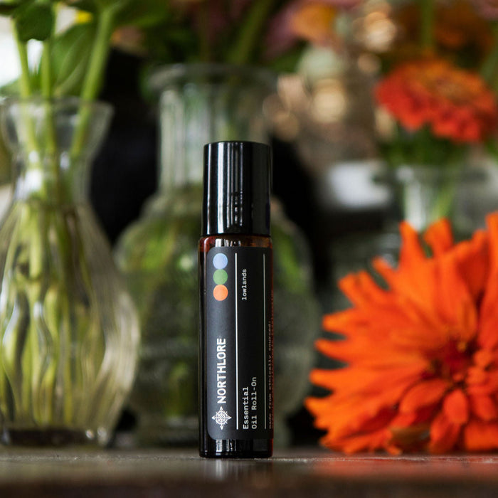 Roll-on bottle of Northlore lowloands on a wooden surface with flowers in the background